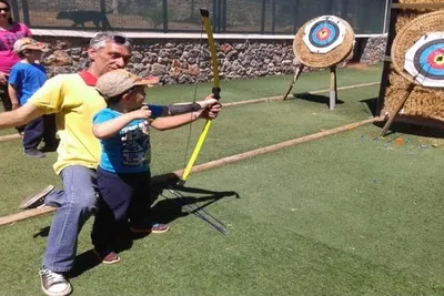 El instructor le enseña al niño a hacer un arco exactamente hacia el objetivo.