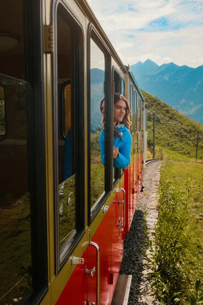 Un viajero disfruta de un medio de transporte inusual desde la ventanilla de un tren en los Alpes suizos.